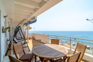 a balcony with a table and chairs and the beach at Ático en primera línea de playa con vistas al mar in Cala del Moral