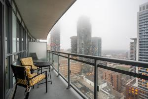 - un balcon avec deux chaises et une table dans un bâtiment dans l'établissement Modern Dunfield Ave Condos by GLOBALSTAY, à Toronto