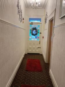 a hallway with a door with a red rug and a window at Villa Guest House in Porthcawl