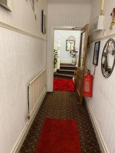 a hallway with a red carpet and stairs with a fire hydrant at Villa Guest House in Porthcawl