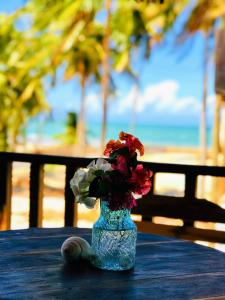 un vase rempli de fleurs assis sur une table près de la plage dans l'établissement Pousada Tangerina, à Icaraí