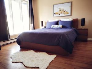 um quarto com uma cama com um edredão roxo e um tapete em Condo sur 2 niveaux avec magnifique vue sur la montagne em Stoneham