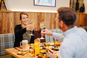 een man en vrouw die aan een tafel wijn drinken bij Pension Linder in Seeboden