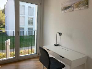 Adliswil的住宿－Private room with work space near Zurich，一张白色的桌子,椅子旁边是窗口