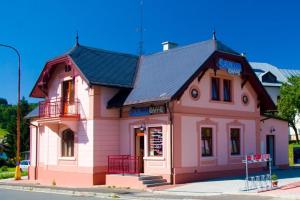 un edificio rosa con tetto nero su una strada di Krakonošovo a Rokytnice nad Jizerou