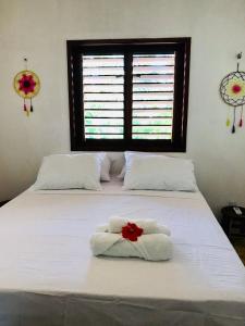 a bedroom with two beds with towels and a window at Pousada Tangerina in Icaraí