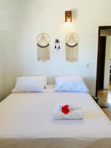 a white bed with a red flower on it at Pousada Tangerina in Icaraí