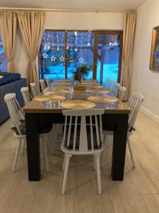 a dining room table with white chairs and a large window at Sowia Enklawa in Ludwikowice Kłodzkie
