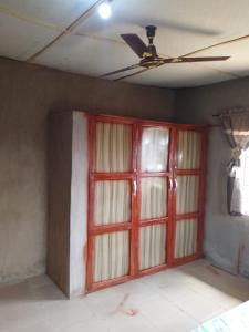een lege kamer met een plafondventilator en deuren bij Abakidoye Lodge in Ilora