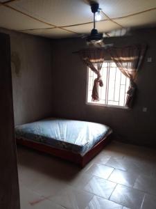 Cama en habitación con ventana en Abakidoye Lodge en Ilora