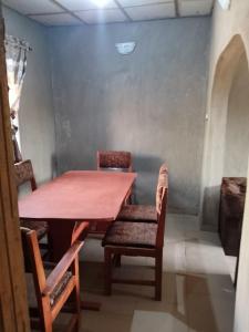 a table and chairs in a room with a wall at Abakidoye Lodge in Ilora