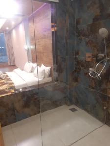 a bathroom with a glass shower with a bed at Manali mountain River Hotel & Resort in Manāli