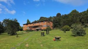 una gran casa de madera en un campo con árboles en Hostal Hunter en Puerto Montt