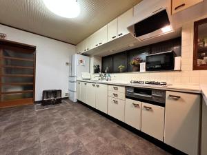 a large kitchen with white cabinets and appliances at 吉祥莊 in Takayama