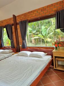 a bedroom with two beds and a large window at Homestay Nam Hàm Luông in Ben Tre
