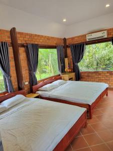 two beds in a room with two windows at Homestay Nam Hàm Luông in Ben Tre