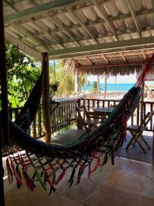a hammock on a porch with the beach in the background at Pousada Tangerina in Icaraí