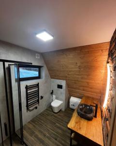 a bathroom with a toilet and a wooden wall at Тихий куточок in Izki