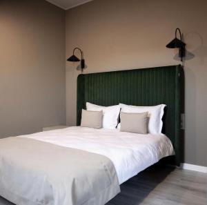 a large bed with a green headboard and white pillows at R.HOTEL in Chernivtsi