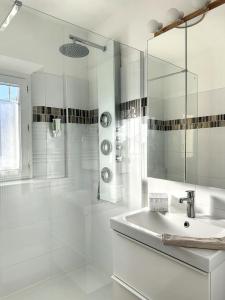 a white bathroom with a sink and a shower at Le Clos de Saint Aygulf in Saint-Aygulf