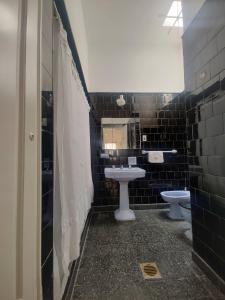 y baño con 2 aseos, lavamanos y espejo. en Limón Dulce Hostel en San Fernando del Valle de Catamarca