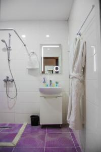 a white bathroom with a sink and a shower at Solo Hotel in Baku