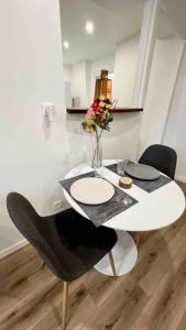 una mesa blanca y sillas con un jarrón de flores en L Eclat - Logement moderne proche Paris - Wifi, en Rueil-Malmaison