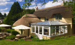 - un bâtiment avec une véranda dotée de tables et d'un parasol dans l'établissement Beck Cottage, Wood Green, New Forest UK, à Breamore