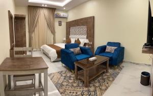 una camera d'albergo con un letto e due sedie blu di كيان المخيم لشقق الفندقية a Najran