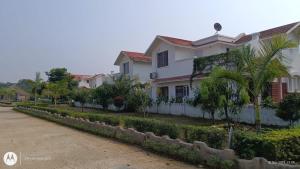 a row of houses with palm trees and a street at Raj Kuthir Homestays - Sobuj Potro in Bolpur