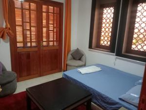 um quarto com uma cama azul, uma cadeira e janelas em Marrakech em Marrakech