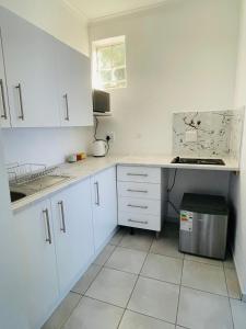 una cucina con armadi bianchi e piano di lavoro di Fafi's Place a Johannesburg