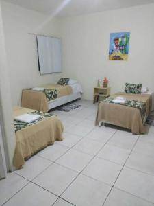 a room with two beds and a white tiled floor at Bom Sossego Pousada DG in Delmiro Gouveia
