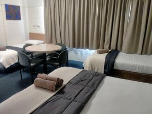 ein Hotelzimmer mit 2 Betten und einem Tisch in der Unterkunft Oakey Motel in Oakey