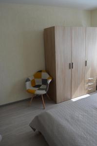 a bedroom with a chair next to a cabinet at Roze Apartment in Rēzekne