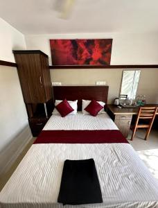 a bedroom with a large bed and a desk at Rio Rooms Calicut in Kozhikode