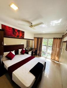 a bedroom with a large bed with red pillows at Rio Rooms Calicut in Kozhikode