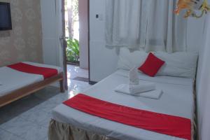 a bedroom with two beds with red and white pillows at Bea's Garden Inn in Puerto Princesa City