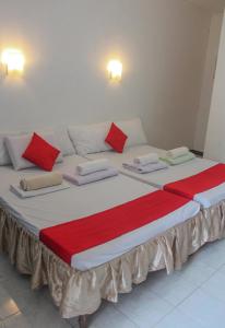 a large bed with red and white pillows on it at Bea's Garden Inn in Puerto Princesa City