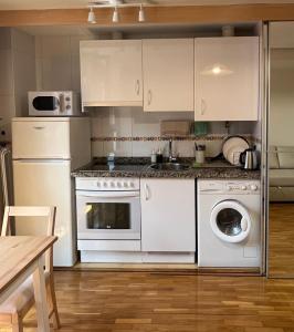 a kitchen with a white stove and a dishwasher at Dúplex Calle Cuba Gijón in Gijón