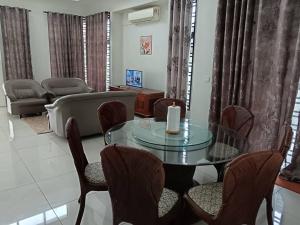 Una sala de estar con una mesa de cristal y sillas. en Dhuha Homestay, en Kampong Kerubong