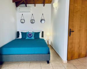a bedroom with a blue bed in a white room at Thalassia Avra Stegna Beach in Archangelos