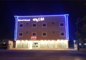 un grande edificio con un cartello illuminato di كيان المخيم لشقق الفندقية a Najran