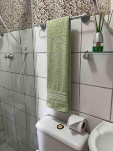 uma casa de banho com um WC e um chuveiro com uma toalha verde em Apartamento Salvador em Salvador