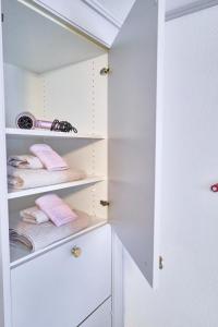 a white closet with white shelves and pink towels at Double Room by Interlaken. Parking in Därligen