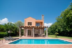 a villa with a swimming pool in front of a house at Olympus Villas in Paralía Skotínis