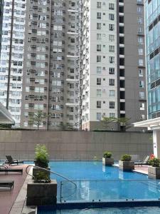 a large swimming pool in a city with tall buildings at Escape 1BR One Uptown BGC w/ Sound System in Manila