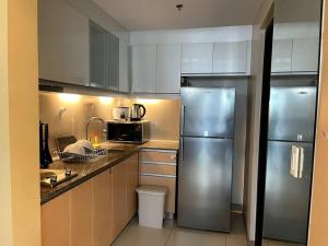 a kitchen with a stainless steel refrigerator and cabinets at Escape 1BR One Uptown BGC w/ Sound System in Manila