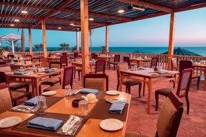 um restaurante com mesas e cadeiras com o oceano ao fundo em Grand Oasis Resort em Sharm El Sheikk