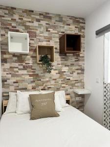 - une chambre avec un lit blanc et un mur en briques dans l'établissement Apartamentos Palma, à Benidorm